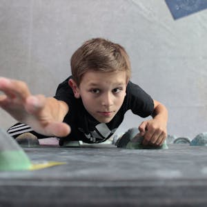 Ein Junge klettert in einer Boulderhalle.