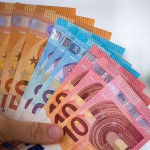 Eine Frau hält Banknoten von 10, 20 und 50 Euro gefächert in der Hand.&nbsp;