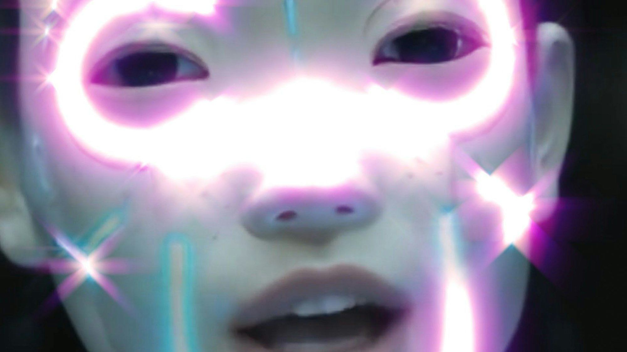 Ein künstlicher Mensch mit lila leuchtenden Wangen schaut in die Kamera.
