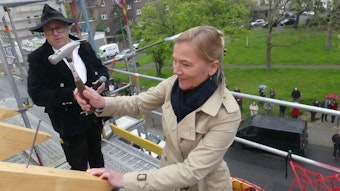 Kathrin Möller schlägt am Dachstuhl des Wohnhauses in Köln Bickendorf einen Nagel mit einem Hammer ein.