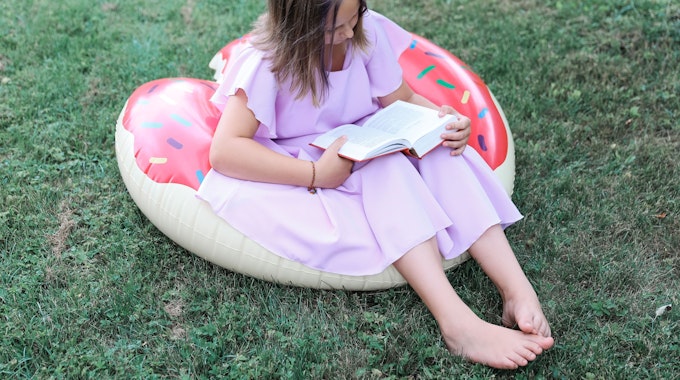 Lesendes Mädchen auf einem aufblasbaren Flamingo.&nbsp;