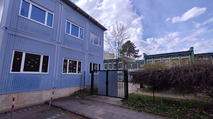 Ein blaues Container-Gebäude mit bunt beklebten Fenstern.