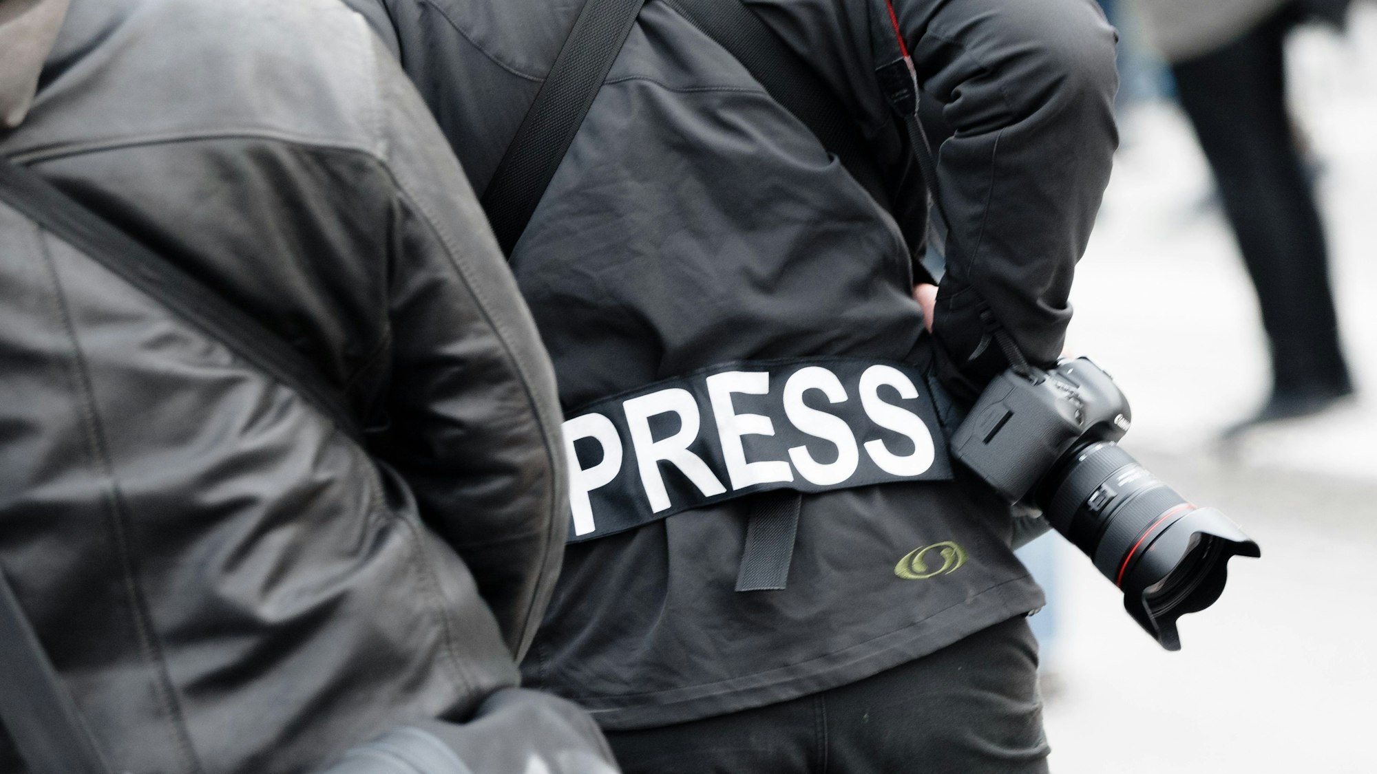 Ein Fotoreporter trägt auf einer Demonstration einen Aufnäher mit dem Text «PRESS» auf seiner Jacke, um sich gegenüber Polizei und Demonstranten als Journalist zu kennzeichnen.