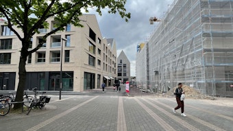Die Porzer Innenstadt mit drei neuen Gebäuden und einer Fußgängerin.