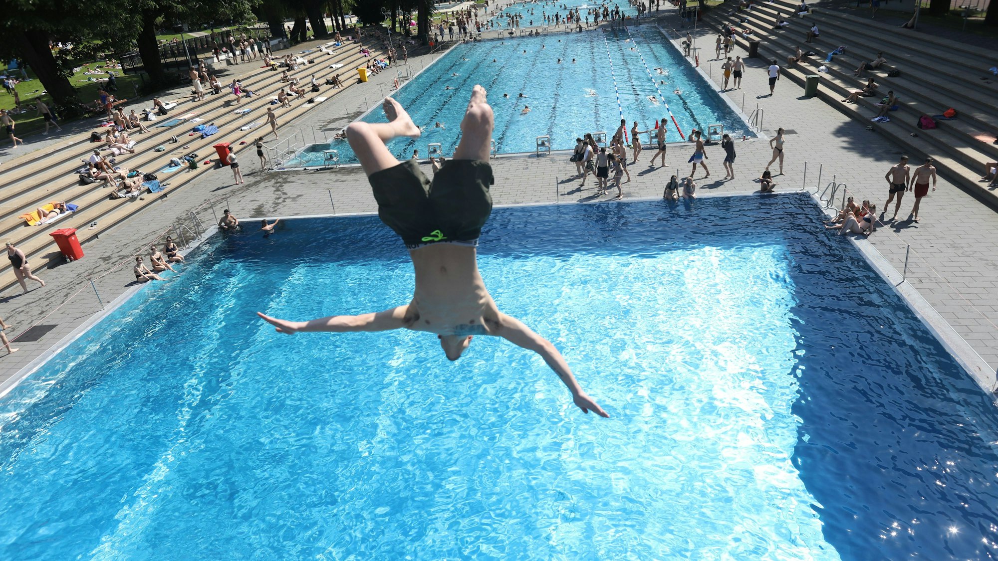 Ein Mann springt kopfüber von einem Sprungturm ins Becken des Stadionbads