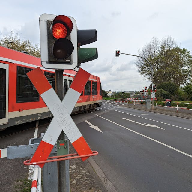 Ein roter Zug der Deutschen Bahn überquert einen Bahnübergang in Hürth.&nbsp;