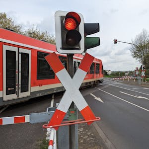 Ein roter Zug der Deutschen Bahn überquert einen Bahnübergang in Hürth.&nbsp;