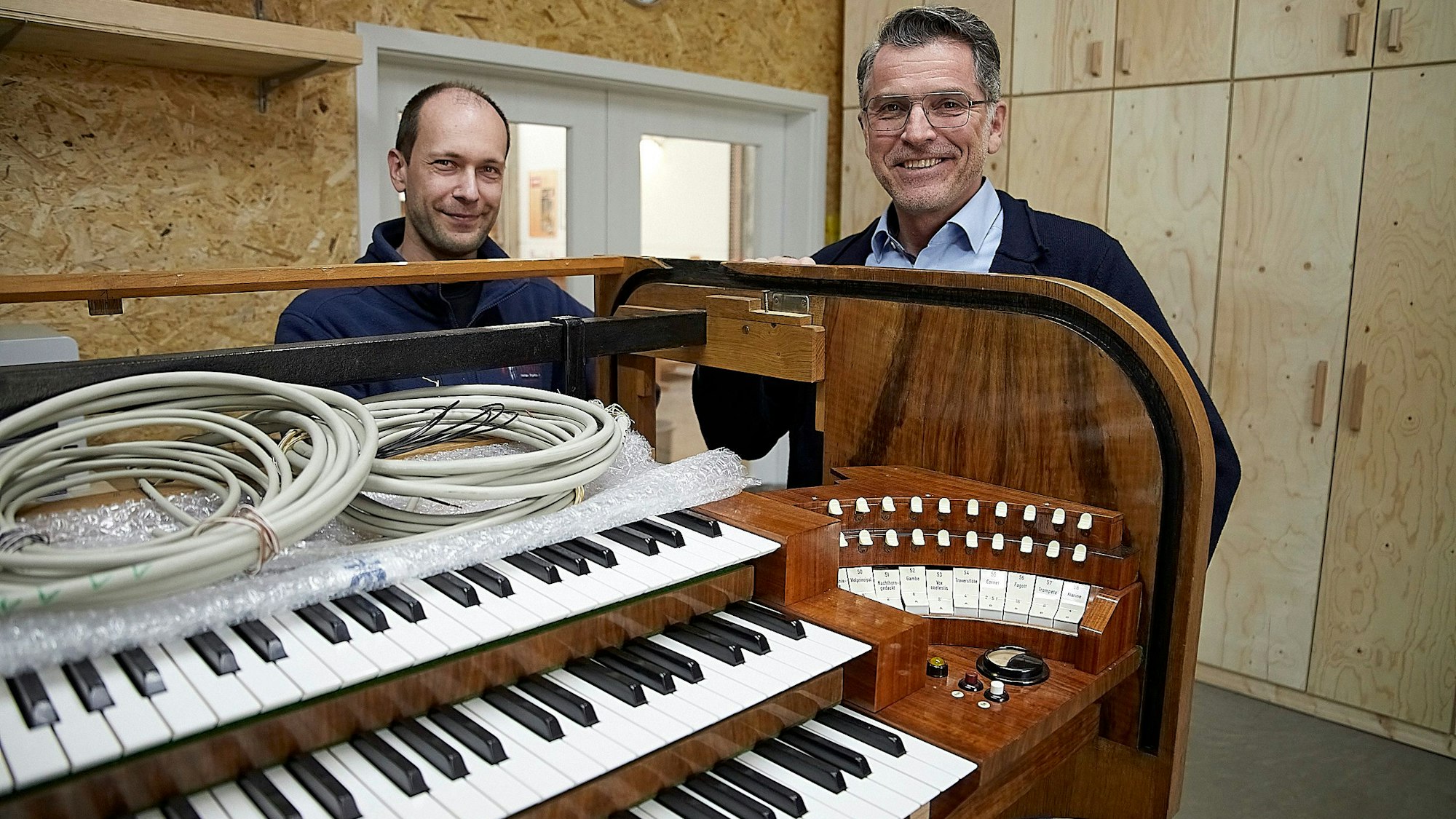 Zwei Männer stehen an einer historischen Orgel, in die nun digitale Technik eingebaut wird.
