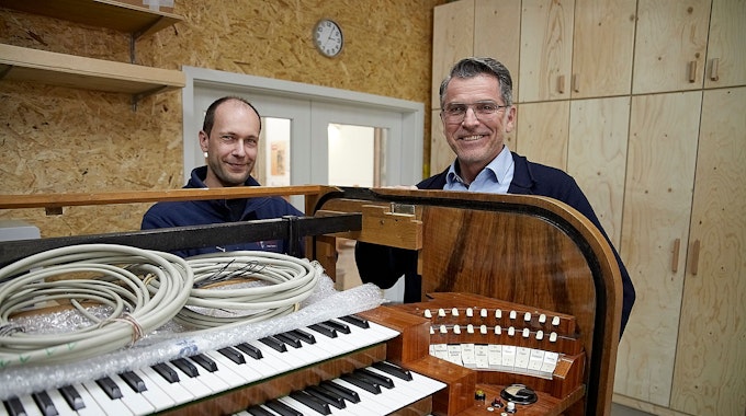 Zwei Männer stehen an einer historischen Orgel, in die nun digitale Technik eingebaut wird.