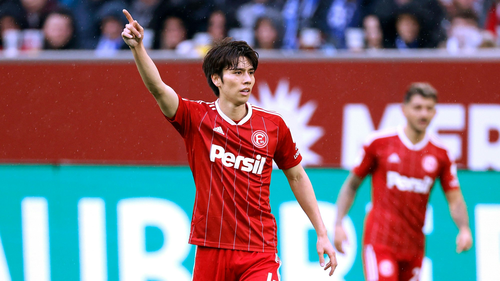 Ao Tanaka steht im Spiel gegen den HSV auf dem Platz und gestikuliert.