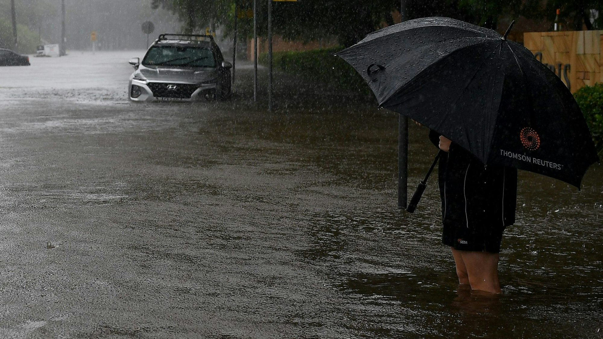 Eine überflutete Straße mit einem Menschen mit Regenschirm.