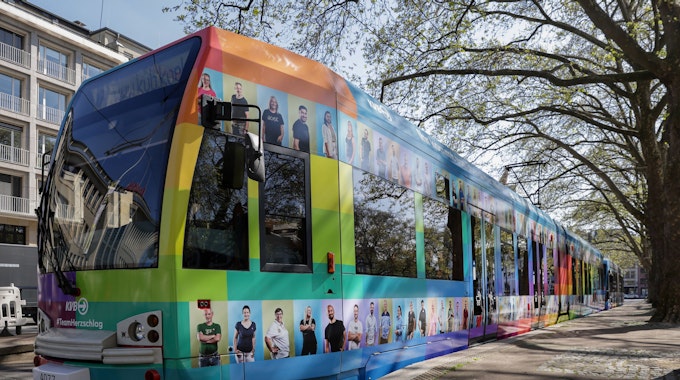Stehende Straßenbahn, die mit bunten Kacheln und Fotos von KVB-Mitarbeitenden beklebt ist