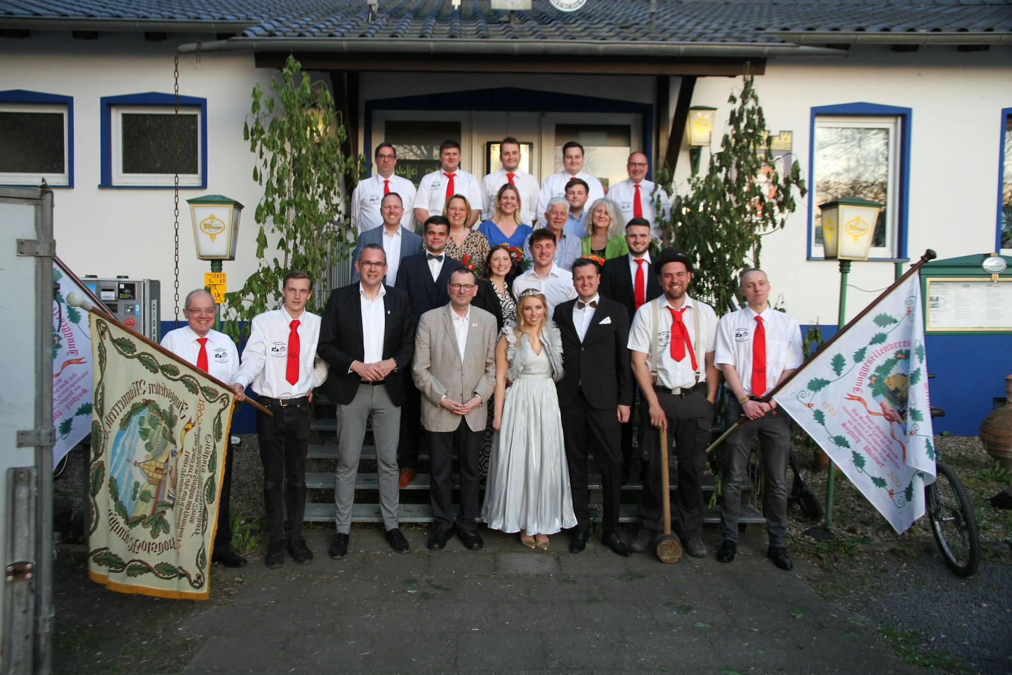 Mitglieder des Junggesellenvereins und Männerreih Eintracht Alt-Wolsdorf stehen vor und auf einer Treppe.