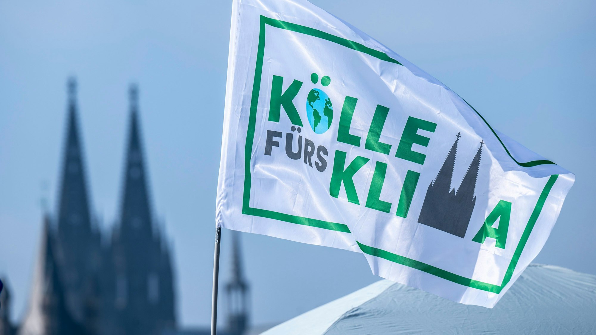 03.03.2023, Köln: Kölle fürs Klima steht auf einer Fahne der Demonstranten. Abschlusskundgebung der Organisation Fridays for Future (Globaler Klimastreik) und Verdi nach einer Demonstration zu Klima- und Verkehrswende. Foto: Uwe Weiser