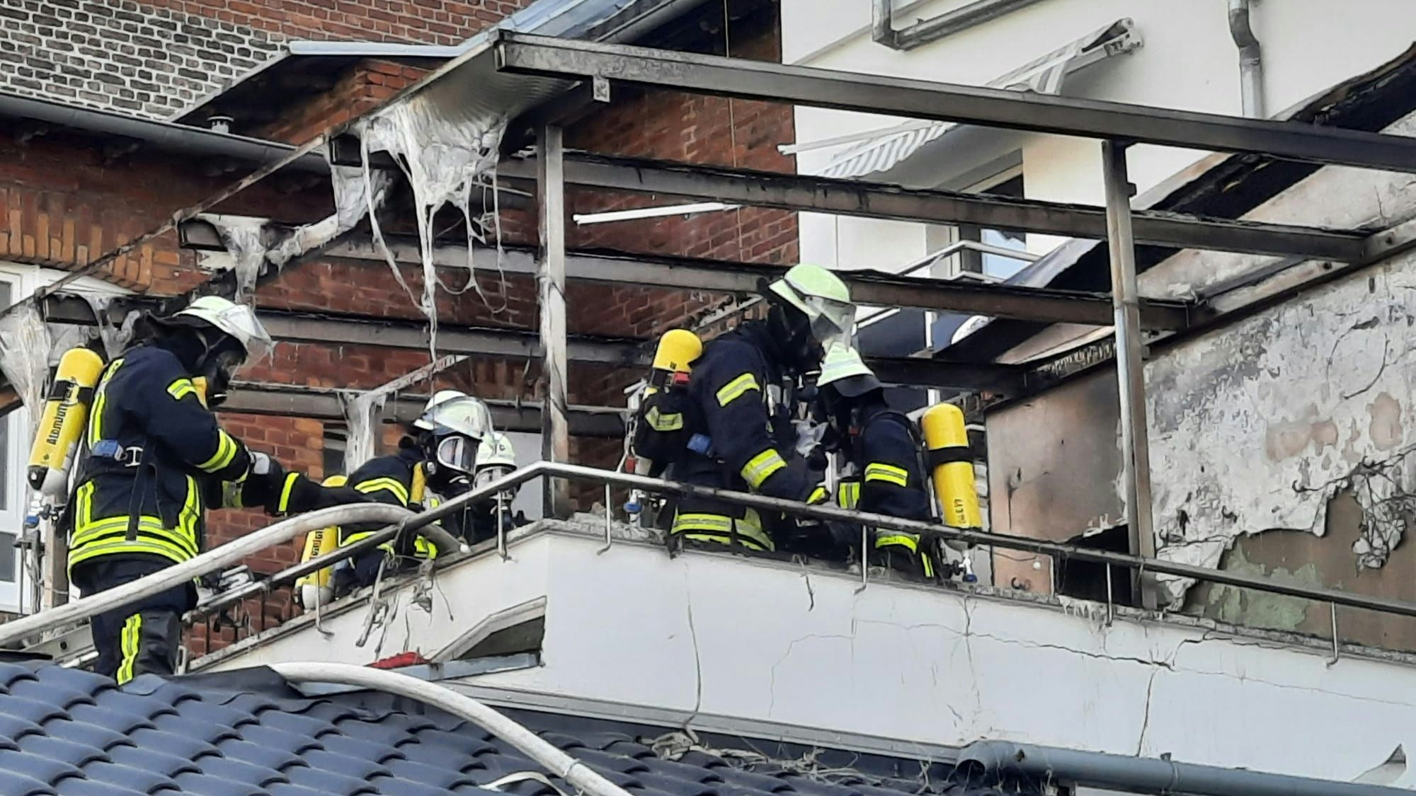 Feuerwehrleute auf einer Terrasse in Königswinter. Der Wintergarten ist komplett ausgebrannt.