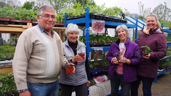 Günter Stadtfeld, Ehefrau Rosemarie, Nachbarin Christa Limbach und Monika Burger-Schmidt stehen mit Tomatenpflanzen in der Hand vor Pflanzregalen.