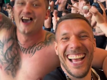 Lukas Podolski feiert mit einem Fan im Ultra-Block.