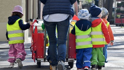 Eine Erzieherin läuft mit mehreren Kleinkindern über einen Bürgersteig&nbsp;