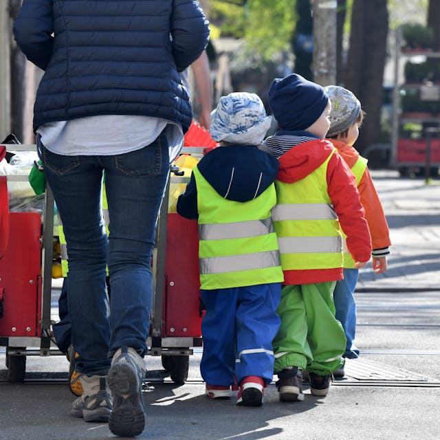Eine Erzieherin läuft mit mehreren Kleinkindern über einen Bürgersteig&nbsp;