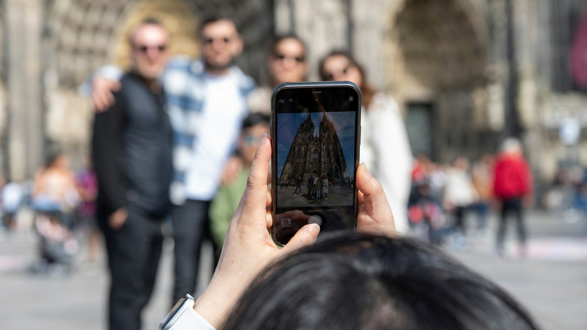 Touristen fotografieren sich mit dem Handy vor dem Dom.