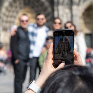 Eine Frau fotografiert Touristen vor dem Dom.