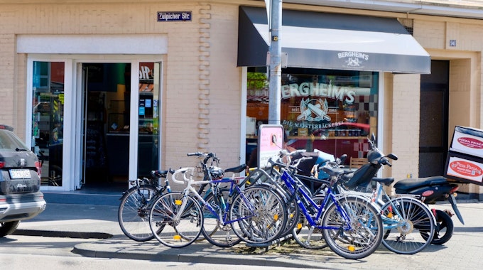 Viele Fahrräder stehen vor der Glasfront eines Eck-Ladenlokals.