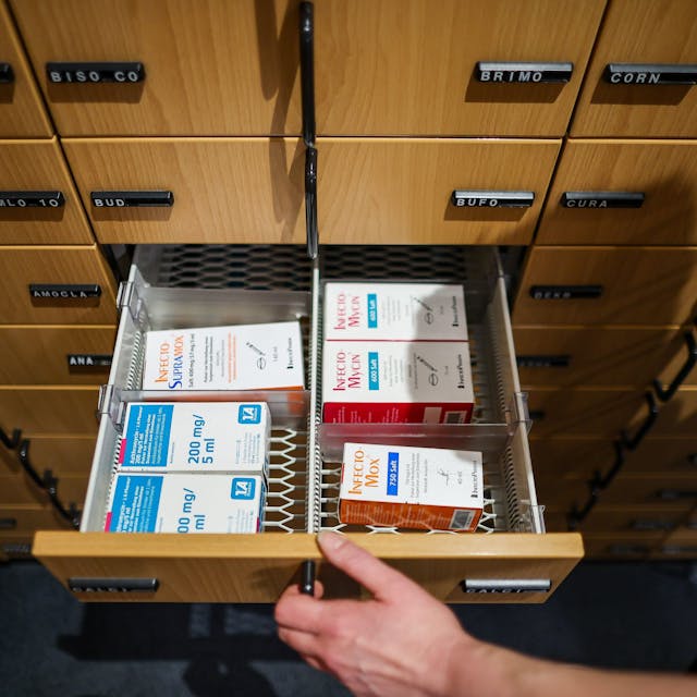 Eine Apothekerin öffnet eine Schublade mit Medikamenten.