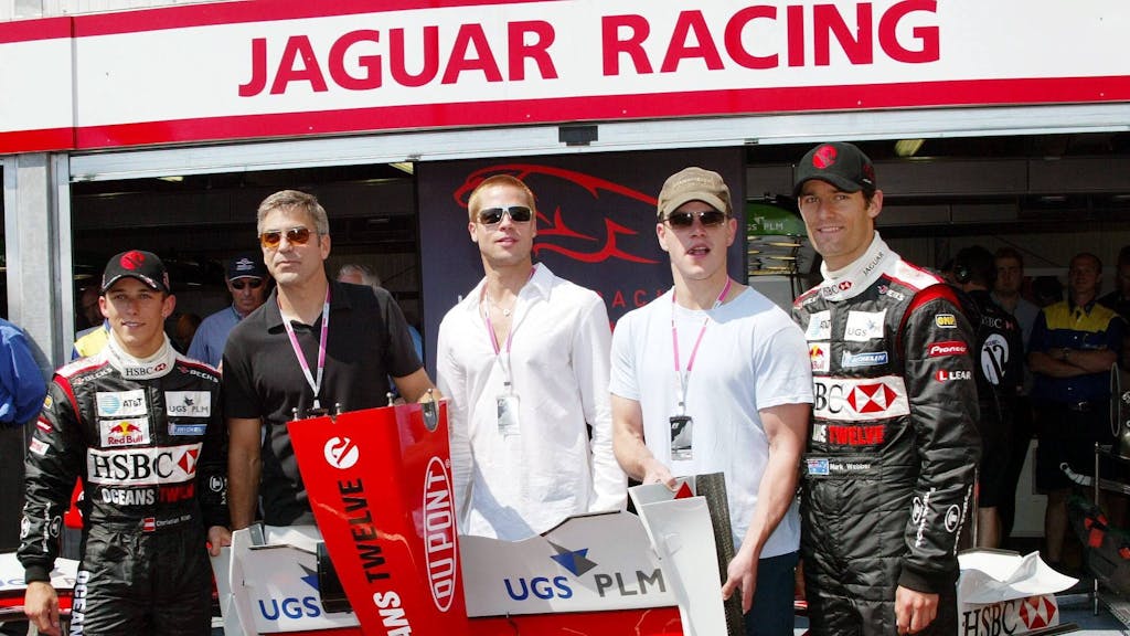 Die Schauspieler George Clooney (2.v.l.), Brad Pitt (Mitte) und Matt Damon (2.v.r.) anlässlich der „Oceans 12“-Filmpromotion zu Gast bei den Jaguar-Cosworth-Piloten Christian Klien (l.) und Mark Webber (r.)