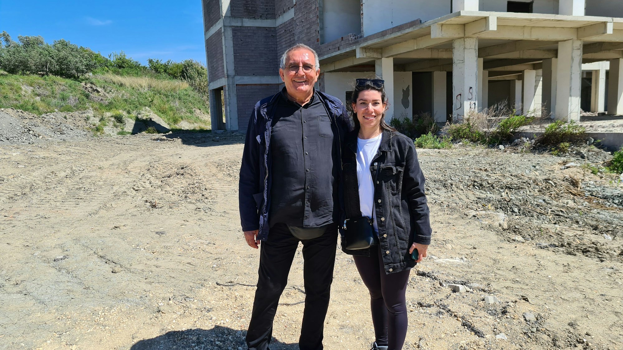 Lamia Faqirzada und Ali Koban stehen auf einem Grundstück im Erdbebengebiet in Hatay, auf dem die Kölner eine spendenfinanzierte Kita bauen wollen.