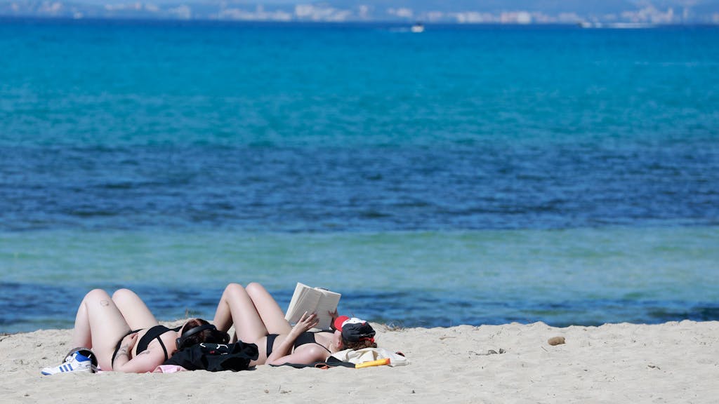 Zwei junge Frauen genießen am 9. April 2023 die Sonne an der Playa de Palma auf Mallorca und sonnen sich.