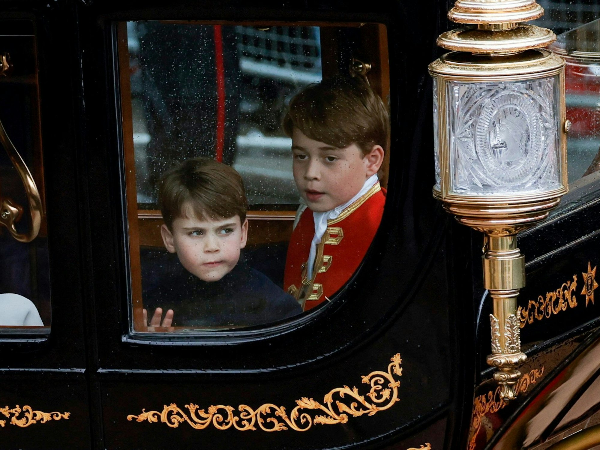 Prinz George (r) und sein Bruder Prinz Louis, fahren nach der Krönungszeremonie von König Charles III. und Königin Camilla im Westminster Abbey in einer Kutsche zum Buckingham Palace zurück.