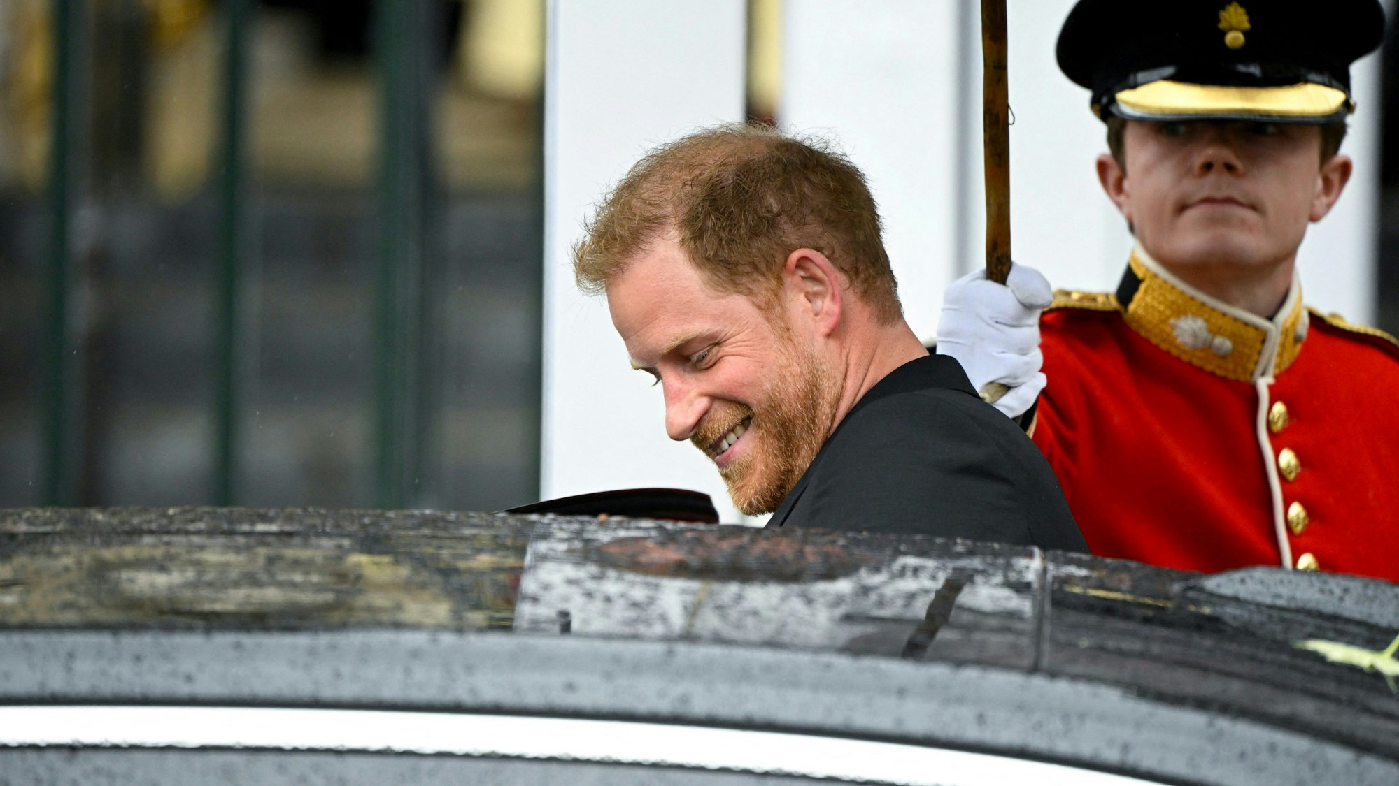Prinz Harry, Herzog von Sussex, verlässt nach der Krönung von König Charles III. und Königin Camilla die Westminster Abbey und steigt lächelnd in ein Auto ein.