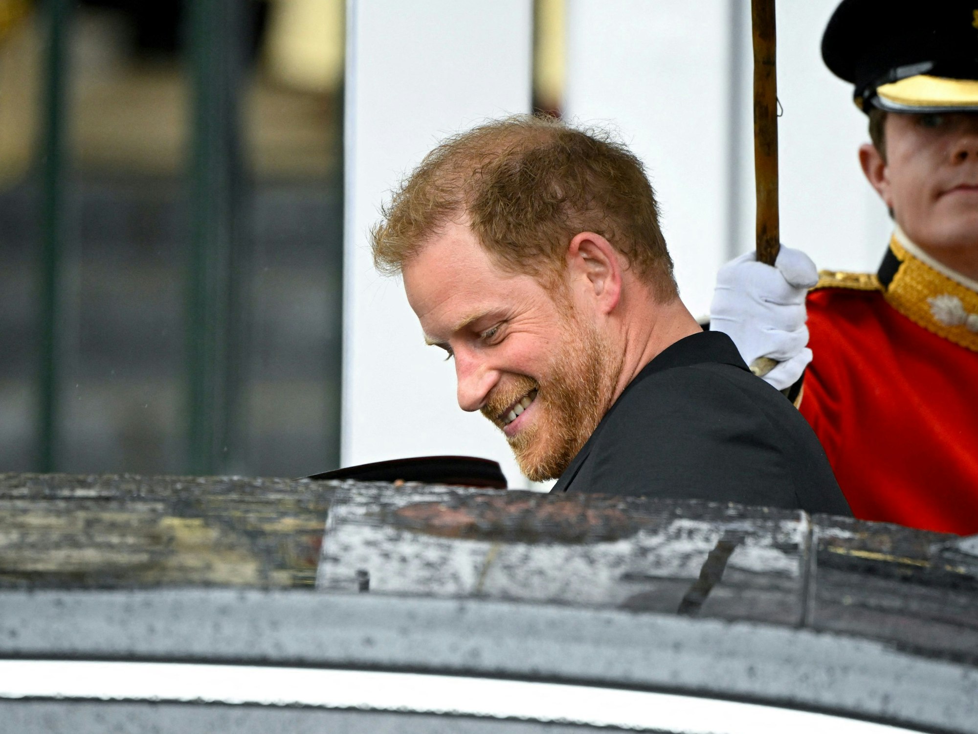 Prinz Harry, Herzog von Sussex, verlässt nach der Krönung von König Charles III. und Königin Camilla die Westminster Abbey und steigt lächelnd in ein Auto ein.