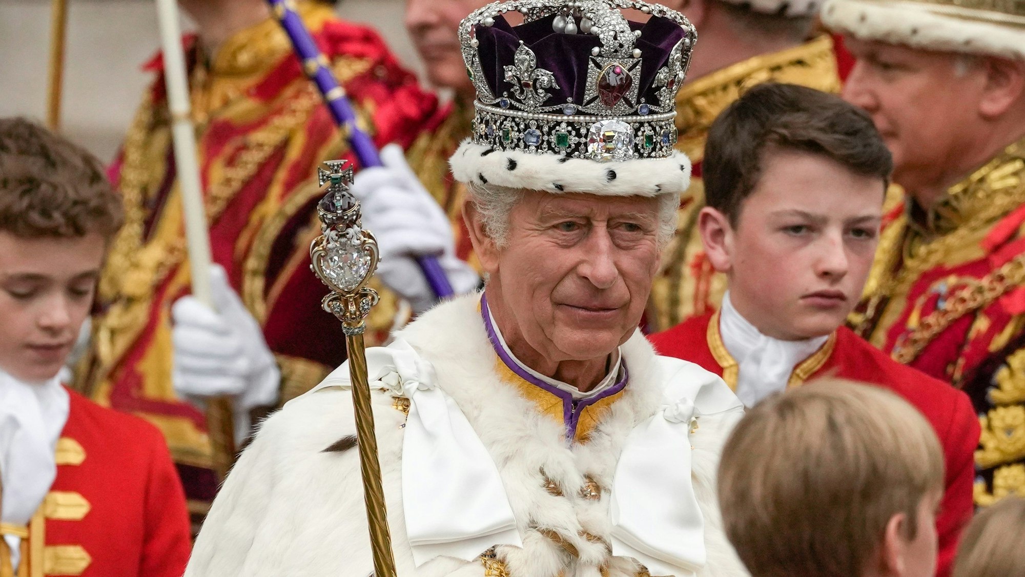 König Charles III. verlässt nach der Krönungszeremonie mit der Imperial State Crown, einem Zepter und dem Reichsapfel die Westminster Abbey.
