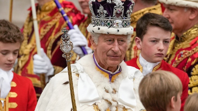 König Charles III. verlässt nach der Krönungszeremonie mit der Imperial State Crown, einem Zepter und dem Reichsapfel die Westminster Abbey.