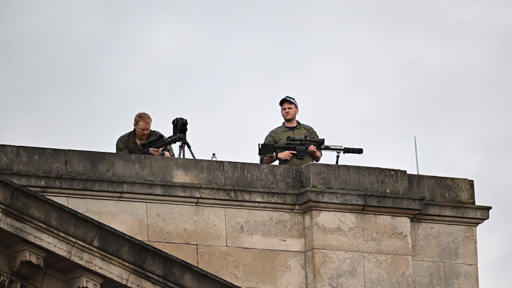 Scharfschützen der britischen Polizei halten ihre Gewehre in der Hand, als sie am 6. Mai 2023 auf dem Dach des Buckingham Palace die Lage im Blick behalten.
