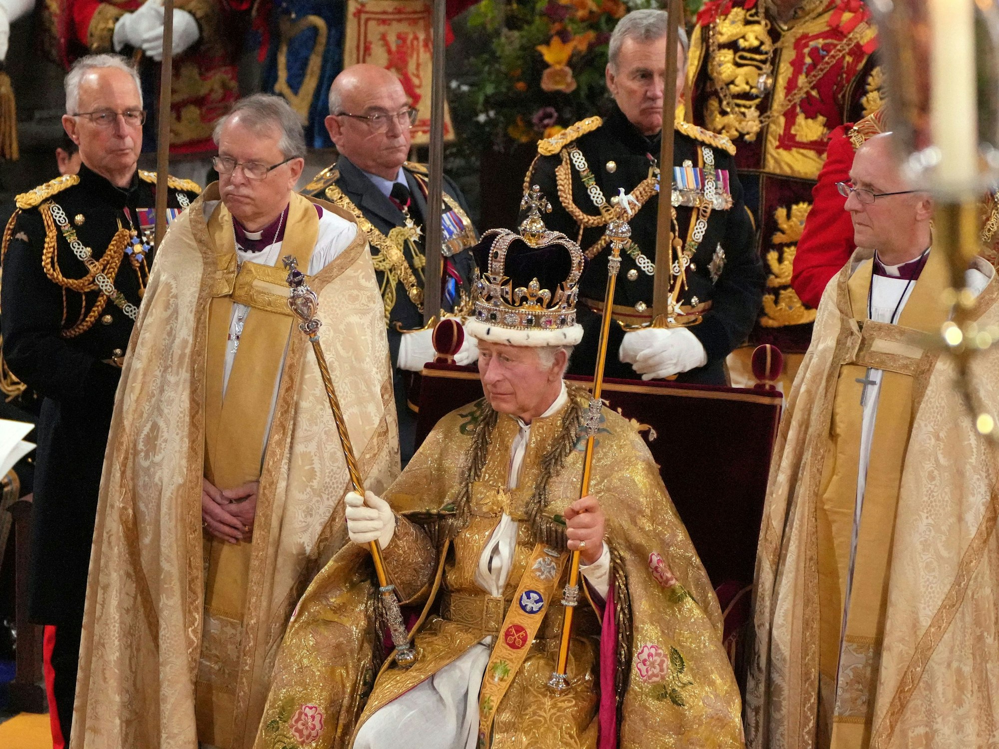 König Charles III. sitzt mit der Edwardskrone und den beiden Zepter auf dem Thron, nachdem er von Justin Welby, Erzbischof von Canterbury, in der Westminster Abbey gekrönt wurde.