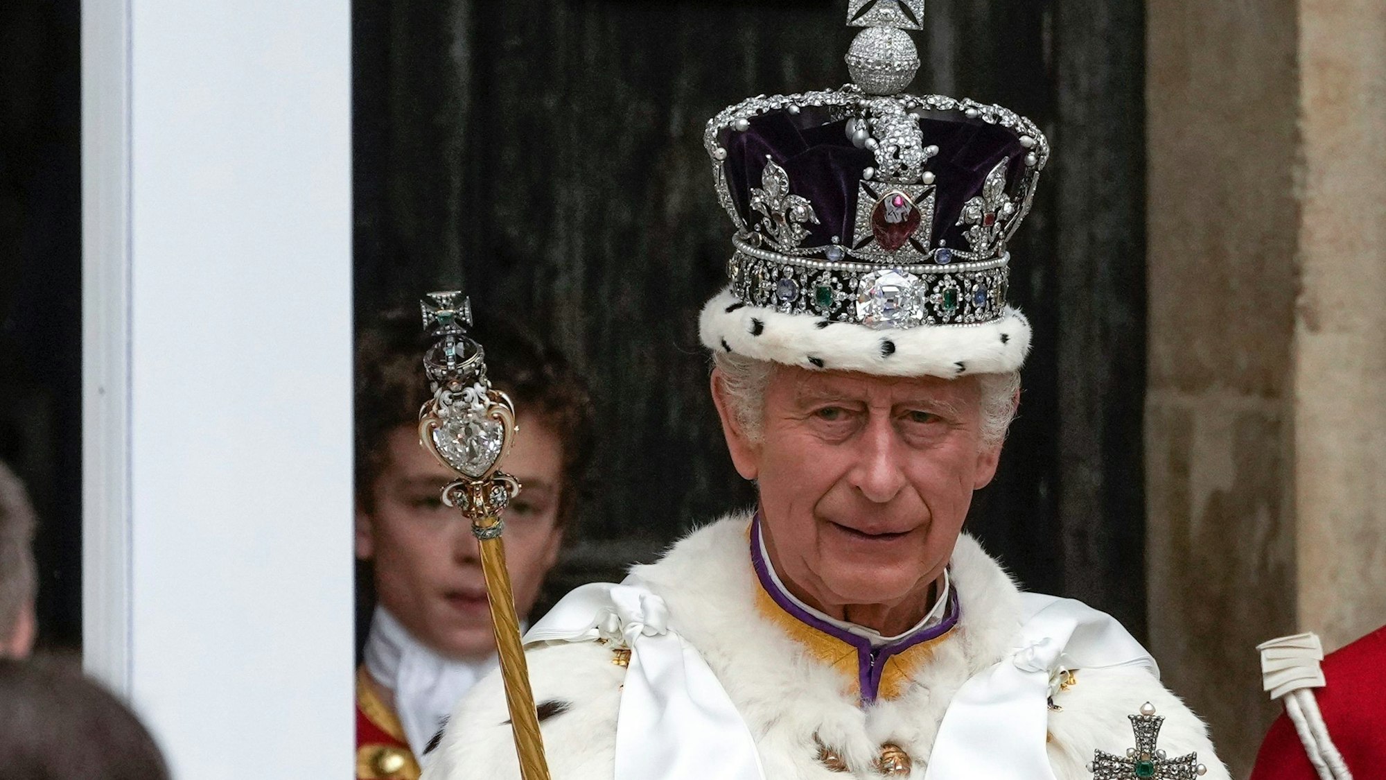 Großbritanniens König Charles III. verlässt nach der Krönungszeremonie mit der Imperial State Crown, einem Zepter und dem Reichsapfel die Westminster Abbey.