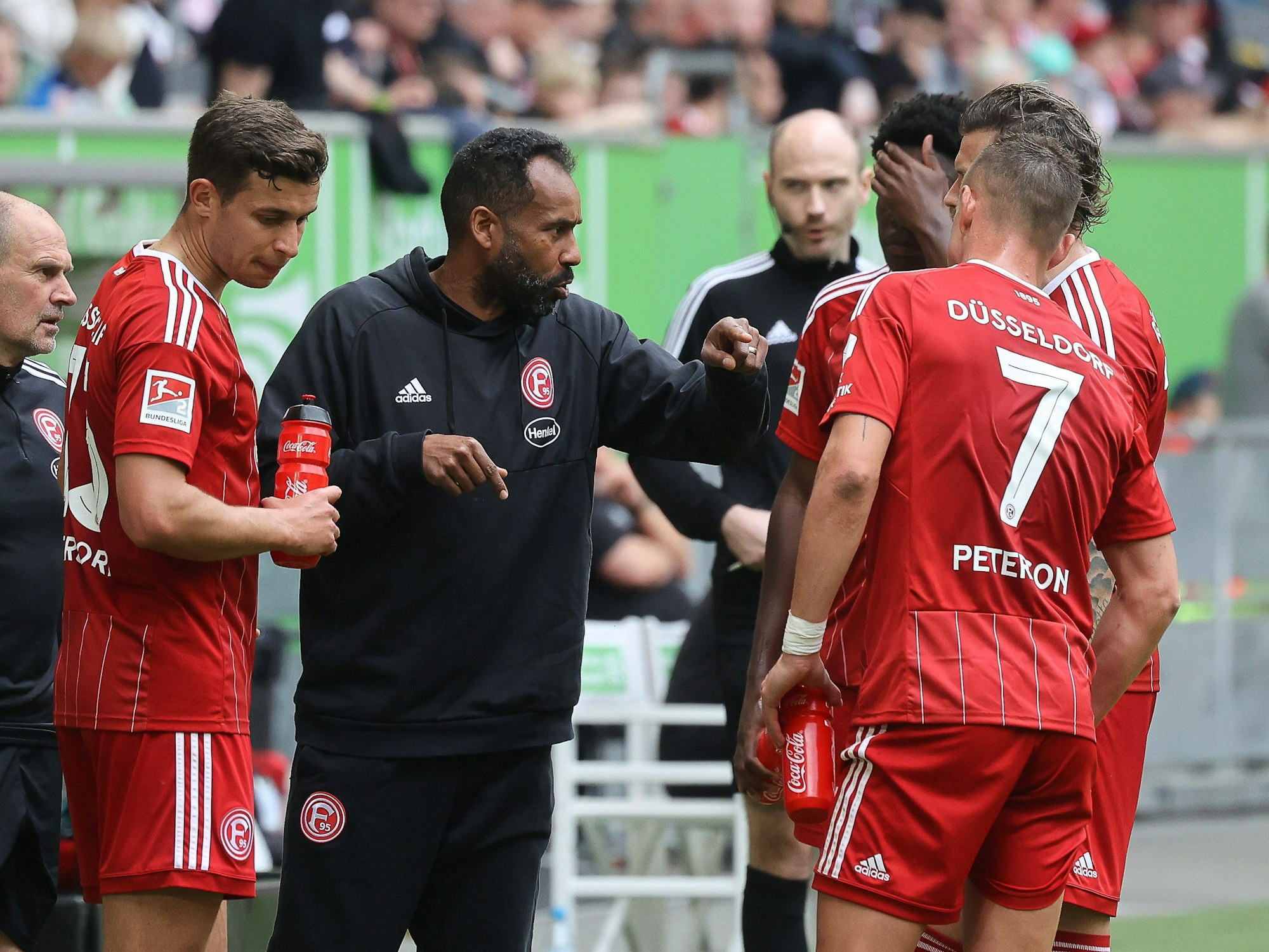 Fortuna Düsseldorfs Cheftrainer Daniel Thioune im Gespräch mit seinen Spielern am Seitenrand.