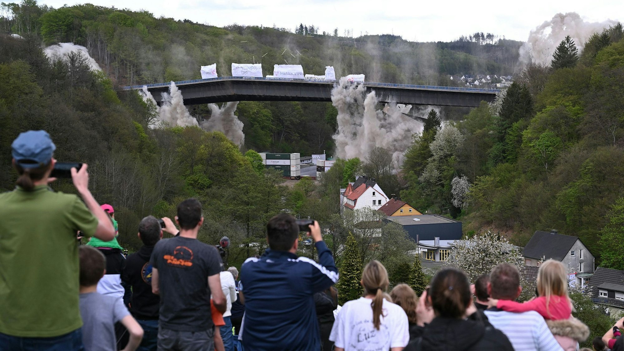 Sprengung der A45-Talbrücke Rahmede: Zuschauerinnen und Zuschauer beobachten und filmen Explosion und Kollaps der Brücke.