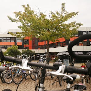Das Bild zeigt das Europagymnasium in Kerpen. Im Vordergrund stehen Fahrräder und Bäume.