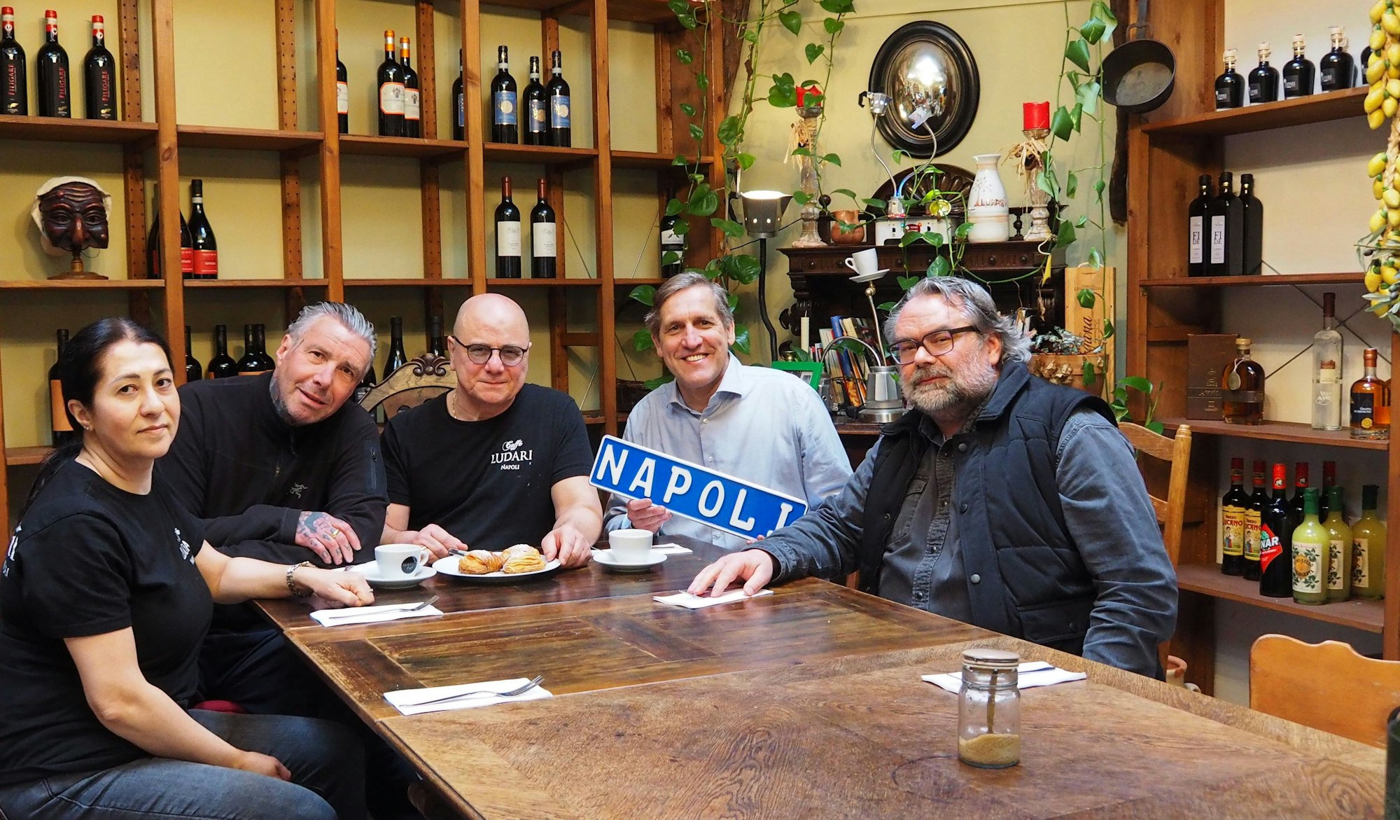 Ludari-Mitarbeiterin, Natalya Karbartay, Rolf Paffenholz, Ciro Rinaldi, Cornel Wachter und Markus Steuer (r.), ein weiterer Stammkunde, sitzen am Tisch im Ludari in Köln-Altstadt-Süd.