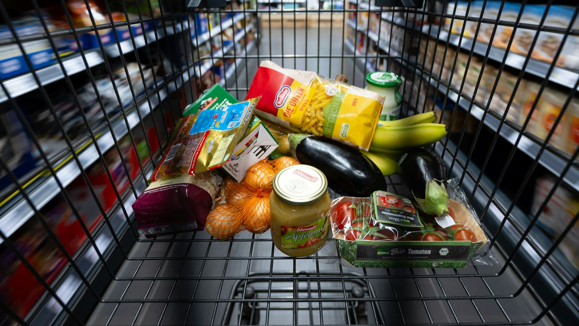 Ein Einkaufswagen mit verschiedenen Lebensmitteln im Supermarkt.