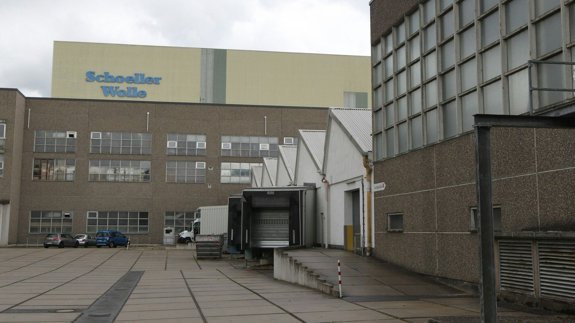 Mehrere Backsteingebäude eines Industriebaus, auf einem Gebäude steht der Schriftzug von Schoeller Wolle.