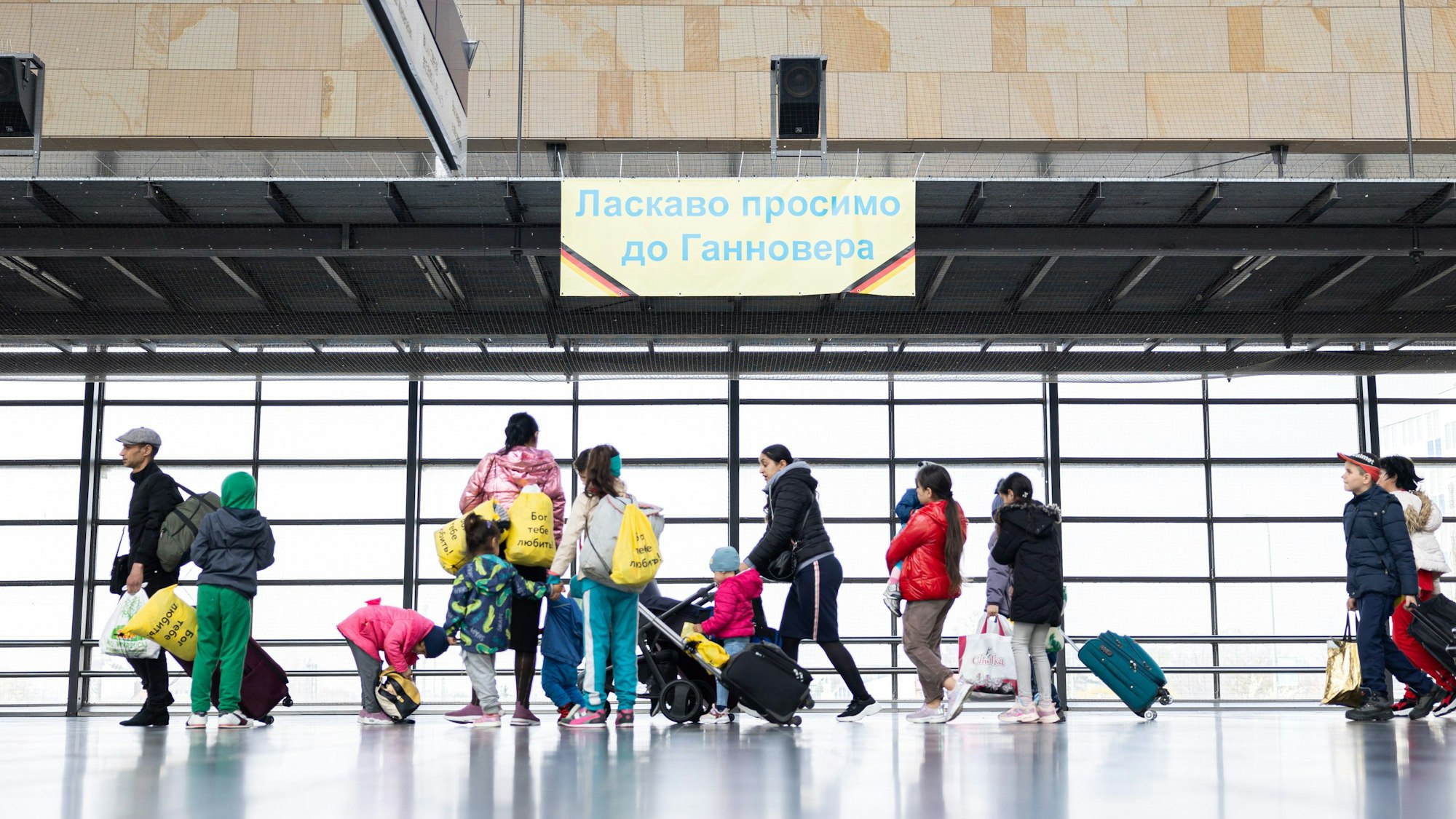 Geflüchtete aus der Ukraine laufen nach ihrer Ankunft durch die Eingangshalle vom Messebahnhof Laatzen in Hannover.