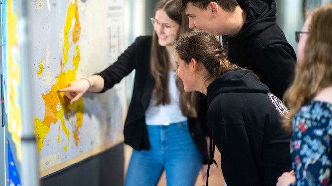 Schüler der Gesamtschule Eifel stehen im Kreishaus vor einer Stellwand der Sonderausstellung zur EU und blicken auf eine Landkarte.