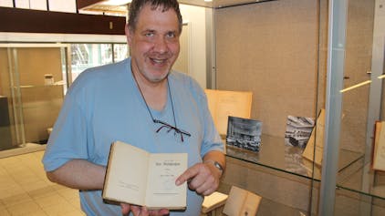 Andreas Freitäger hält ein Buch in den Händen.