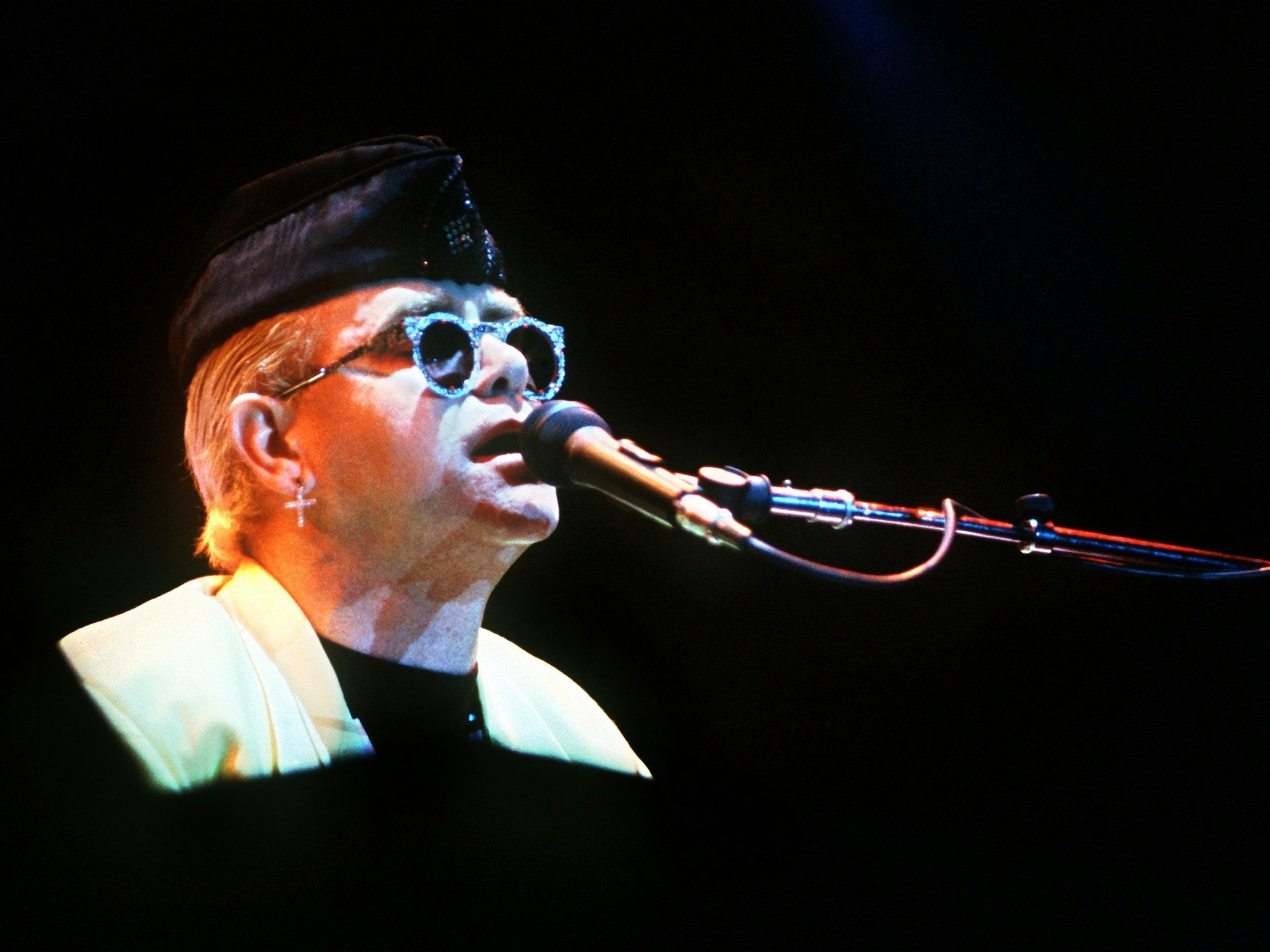 Elton John singt während eines Konzertes ins Mikrofon