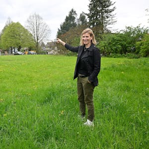 Sabrina Fahlenbock steht auf der Dorfwiese in Moitzfeld und bedeutet mit der Hand, dass hier gut eine Kita gebaut werden könnte.&nbsp;