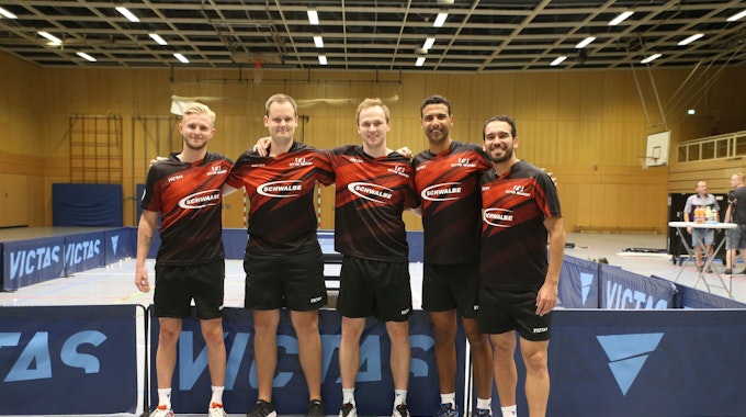 Vier Tischtennisspieler und ihr Trainer stehen Arm in Arm in einer Reihe.